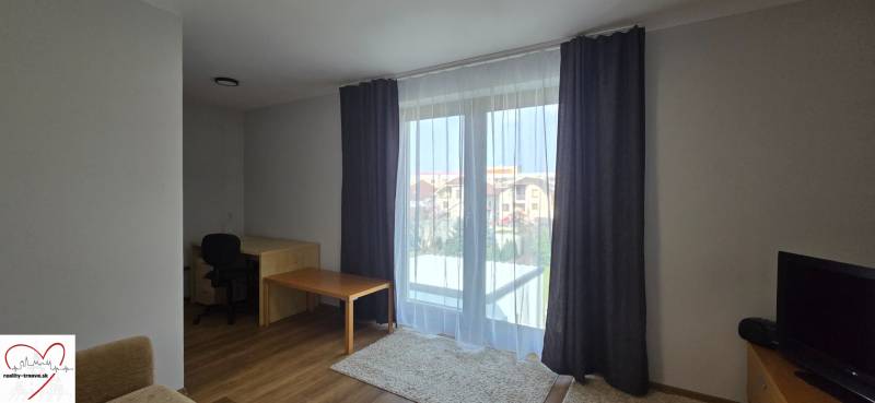 Nappali szoba asztallal és fa dekorpadlóval egy háromszobás lakásban.