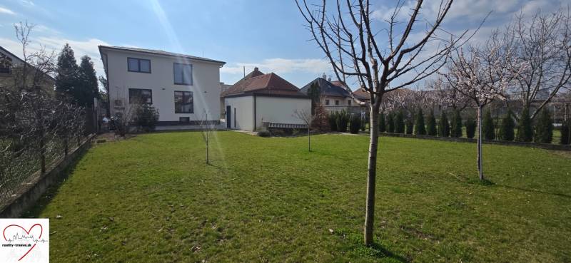 Kert a Gábora Steinera utcai 3 szobás lakásnál, Trnava, fiatal fákkal.