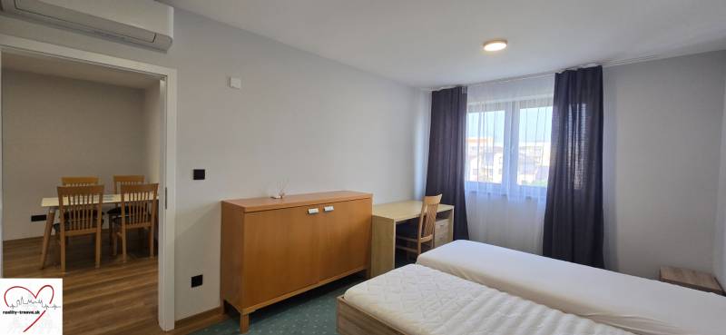 Hálószoba ágyakkal és bútorokkal egy háromszobás lakásban, fehér falak, fa dekor padló.