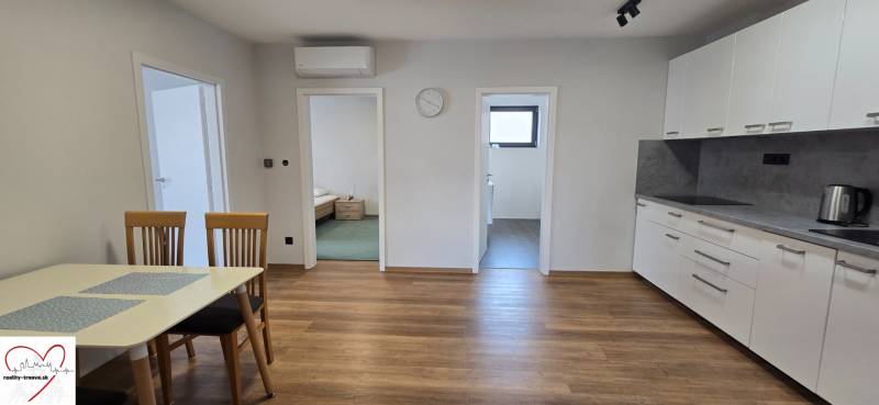 Konyha egy 3 szobás lakásban fa mintázatú padlóval és étkezőasztallal.