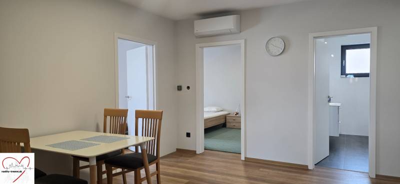 Étkezőasztal székekkel és fa dekorációjú padló a háromszobás lakásban.