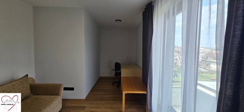 Szoba egy háromszobás lakásban, fa dekorációjú padlóval, asztallal és kanapéval.