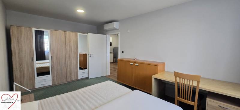 Hálószoba egy háromszobás lakásban franciaággyal, szekrénnyel és asztallal.