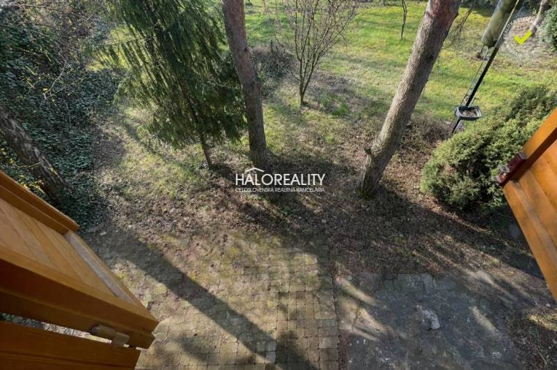 Újlót községben, a ház mellett van egy kert, ahol térkő és fák találhatók.