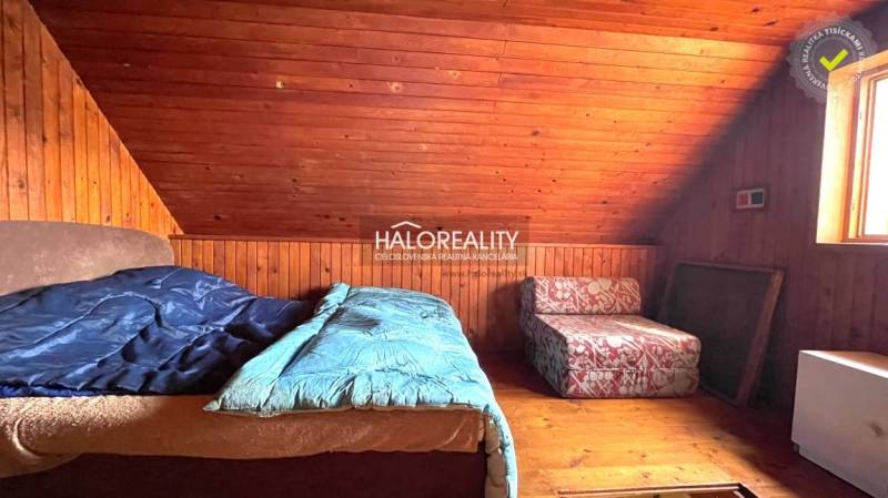 Tetőtéri szoba faházzal, faburkolattal és két ággyal.