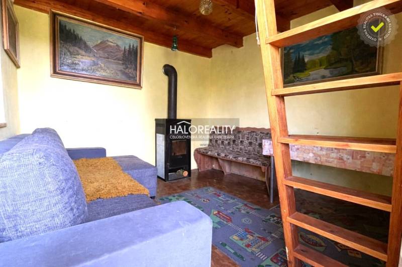 A ház belseje kandallóval, fa mennyezettel és lépcsővel a tetőtérbe.