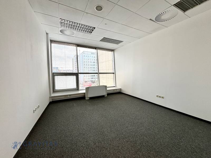 Üres iroda szőnyegpadlóval és nagy ablakokkal.