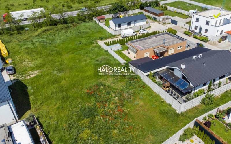 Kilátás a szenci lakóövezeti füves telkekre, családi házakkal körülvéve.