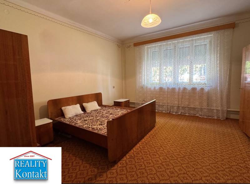 Ágy fotellel és éjjeliszekrényekkel a hálószobában, szőnyeggel.