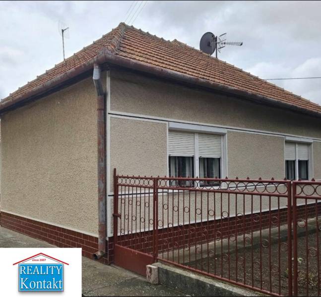 Családi ház Radaván, a Fő utcán, piros tetővel és fehér zsalugáterekkel.