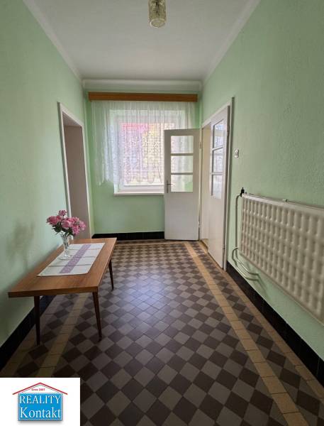 Egy családi ház folyosója, asztalon virágokkal és csempézett padlóval.