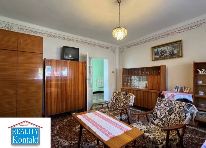 Nappali egy családi házban szőnyeggel, régebbi bútorokkal és csillárral.