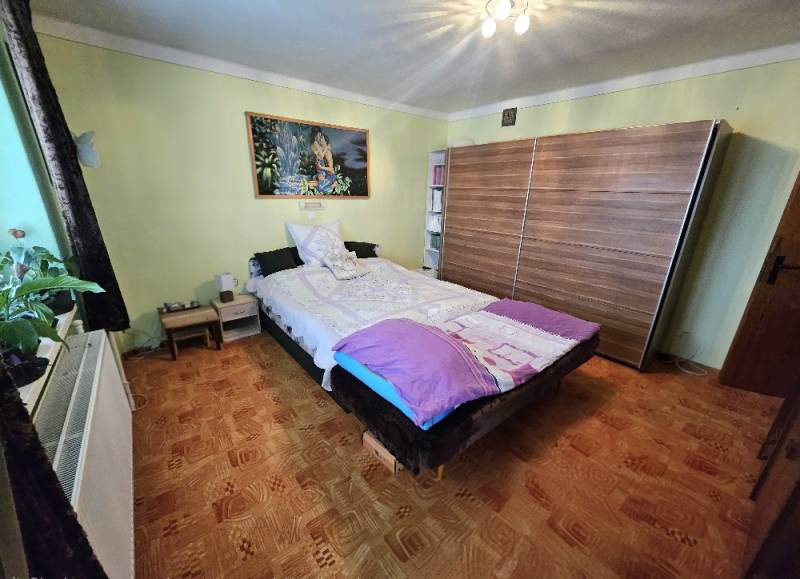 Hálószoba családi házban, ággyal, szekrénnyel és fa dekorációjú padlóval.