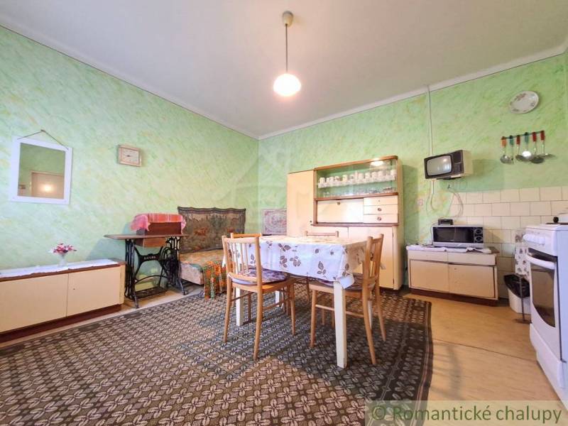 Családi ház belső tere étkezőasztallal, fotellel és retro televízióval.