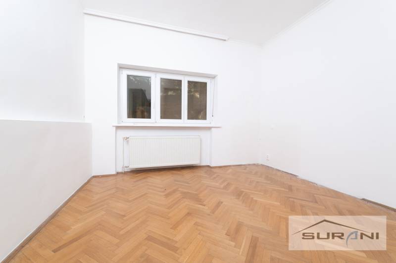 Szoba egy 4 szobás lakásban fehér falakkal és fa dekoros padlóval.