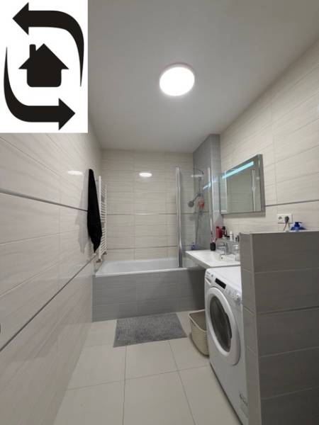 Fürdőszoba egy kétszobás lakásban zuhanyzóval, káddal és mosógéppel.