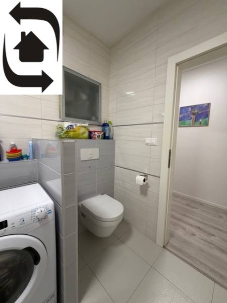 Fürdőszoba mosógéppel, WC-vel és csempével egy kétszobás lakásban.