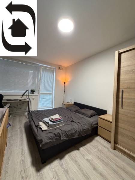 Hálószoba egy kétszobás lakásban fa dekorációjú padlóval és az ablak melletti ággyal.