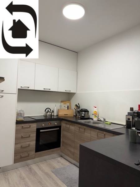 Konyha egy kétszobás lakásban, fa hatású padlóval és fehér szekrényekkel.