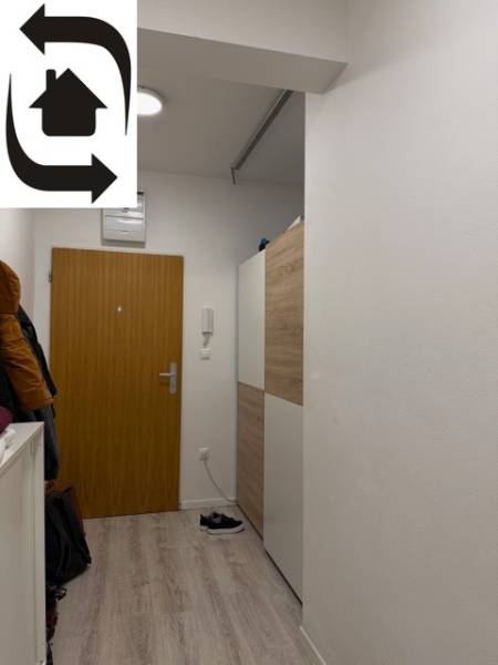 Előszoba egy kétszobás lakásban, fehér falak és ajtók, fa dekoros padló.