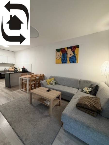 Nappali rész egy kétszobás lakásban kanapéval, asztallal és étkező sarokkal.