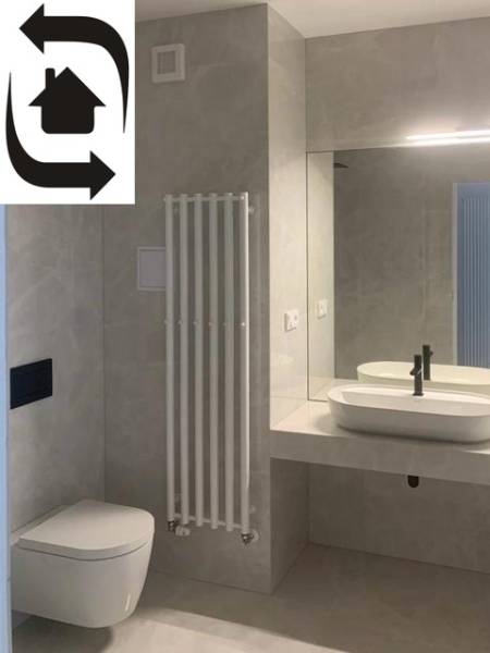 Modern fürdőszoba egy kétszobás lakásban tükörrel, mosdóval és WC-vel.