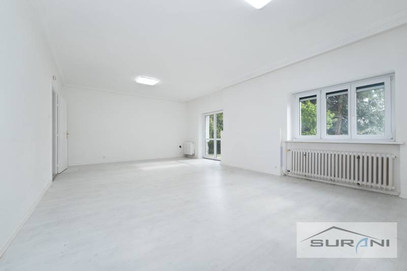 Tágas nappali egy 4 szobás lakásban fehér padlóval és nagy ablakokkal.