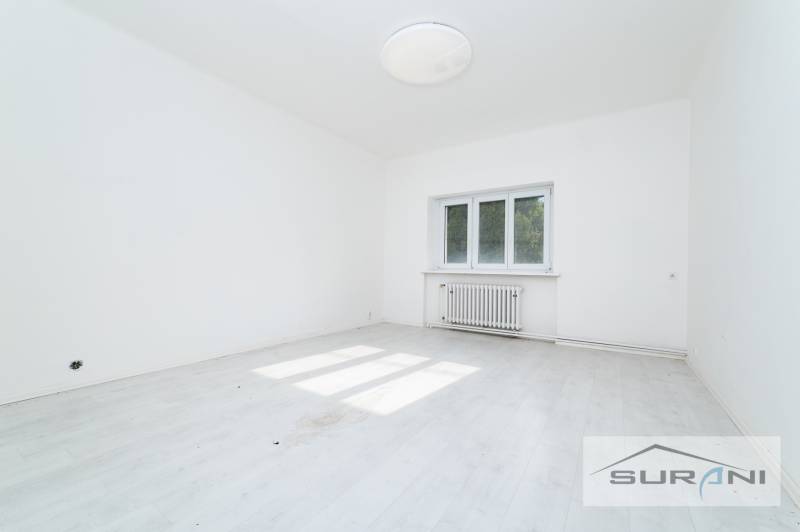 Üres szoba fehér falakkal és fa dekorációjú padlóval egy 4 szobás lakásban.