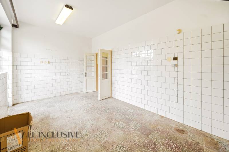 Üzlethelyiség csempézett fallal és fehér ajtókkal, egyszerű tér.