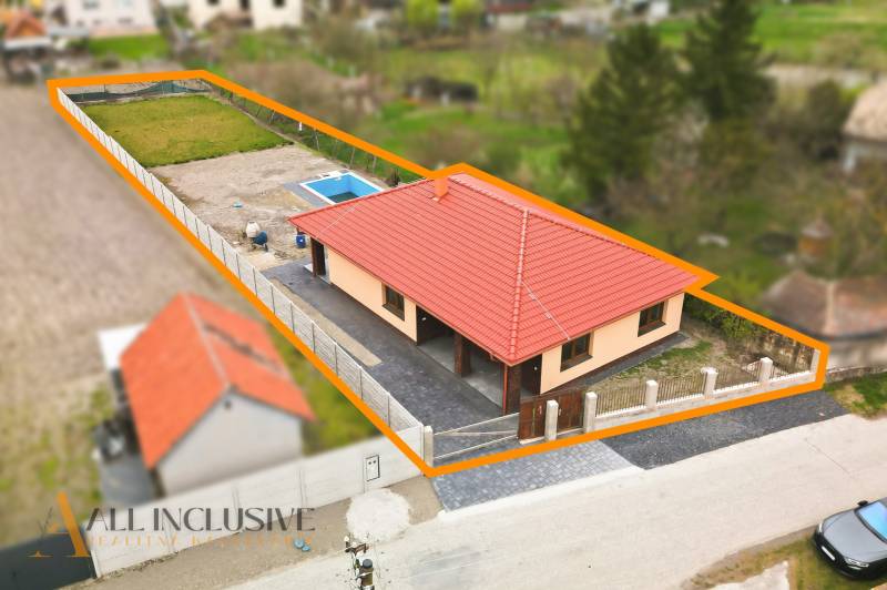 Családi ház Felsővámoson piros tetővel és medencével az udvaron.