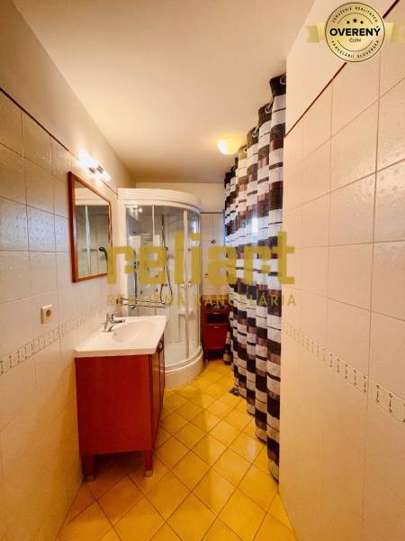 Fürdőszoba családi házban mosdóval, zuhanyzóval és csempével.