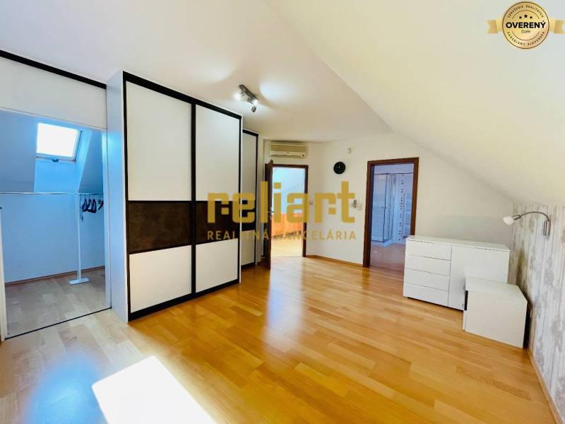 Tetőtéri szoba fa dekoros padlóval és beépített szekrénnyel egy családi házban.