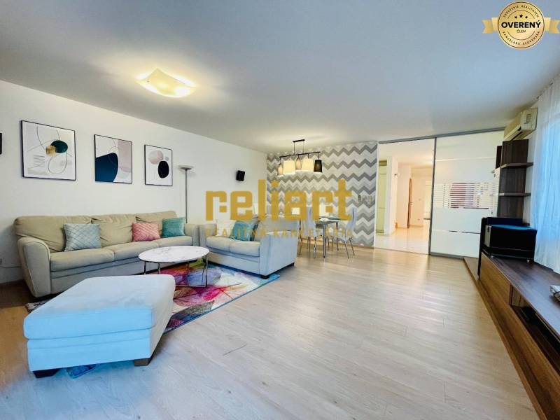 Nappali egy családi házban kanapéval, dekorációkkal és fa mintázatú padlóval.