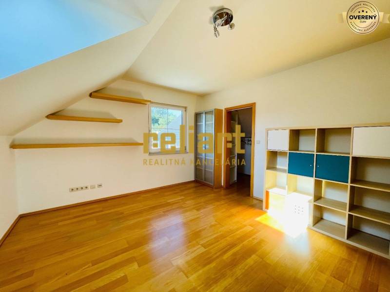 Szoba egy családi házban fa dekoros padlóval, polcokkal és polcos szekrénnyel.