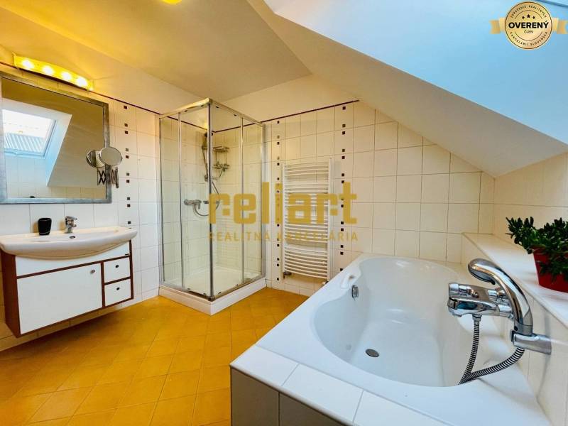 Családi ház fürdőszobája káddal, zuhanyzóval és ferde mennyezettel.