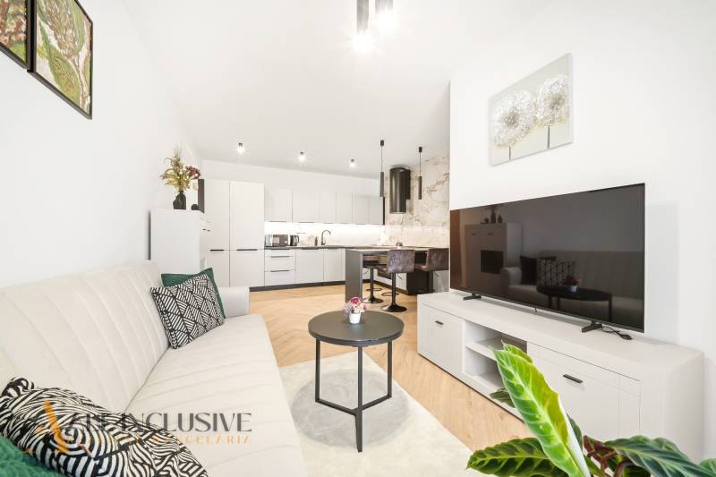 Nappali konyhával egy 4 szobás lakásban, fa hatású padlóval.