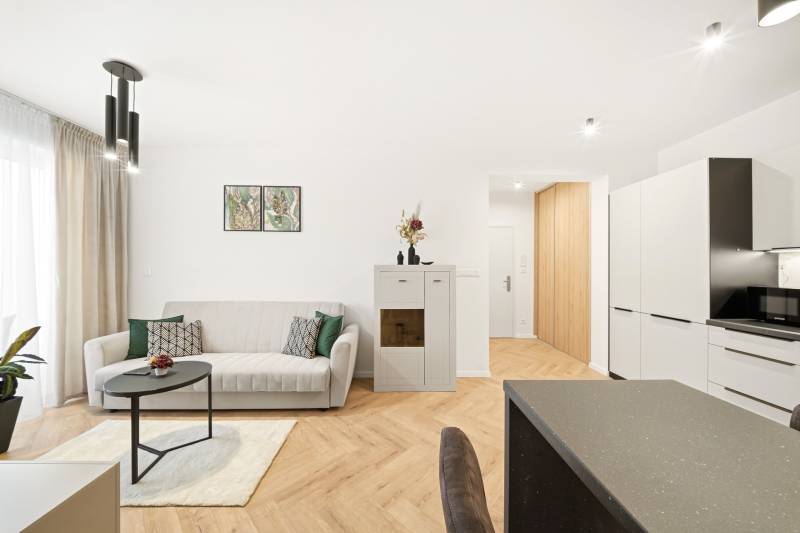 Nappali egy négy szobás lakásban fehér kanapéval és fa mintázatú padlóval.