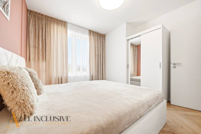 Világos hálószoba egy 4 szobás lakásban fehér szekrénnyel és függönyökkel.