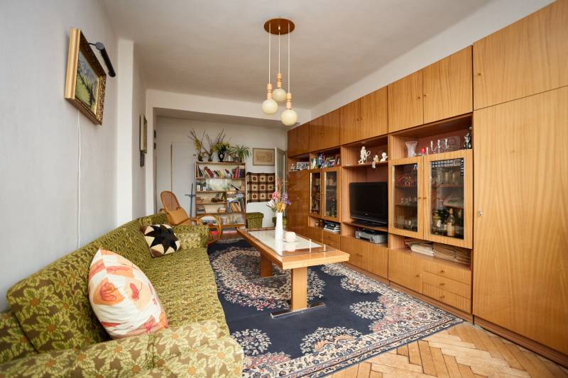 Nappali egy háromszobás lakásban, szőnyeggel és fa dekorációjú padlóval.