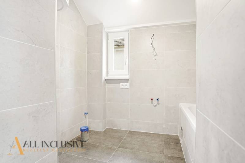 Fürdőszoba családi házban nagy formátumú világos csempékkel.