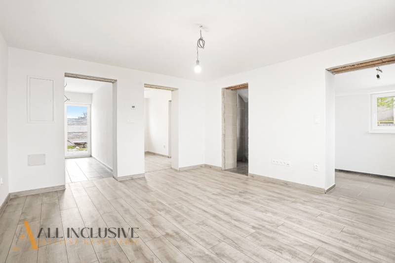 Családi ház belső tere fa dekorációjú padlóval és tiszta fehér falakkal.