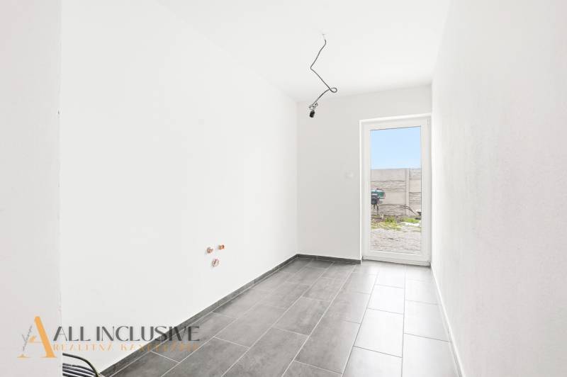 Családi ház belső tere csempével, fehér falakkal és teraszra nyíló ajtókkal.