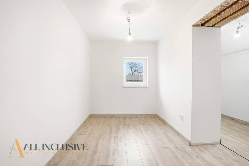 Szoba egy családi házban fehér falakkal és fa dekorációjú padlóval.