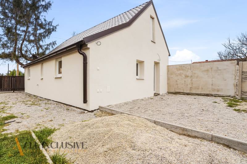 Családi ház Alsóvámoson fehér homlokzattal és ferde tetővel, kavicsos telken.