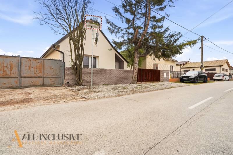 Családi házak Dunaradványon kerítéssel és az út mentén parkoló autókkal.