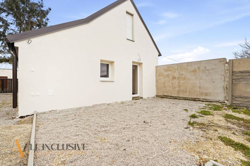 Családi ház Alsóvámoson fehér homlokzattal és kavicsos udvarral.