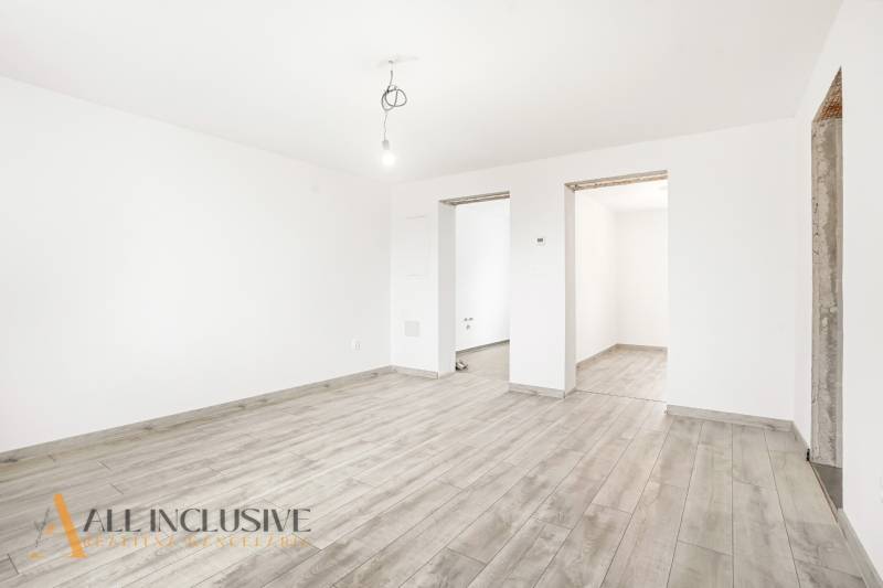 Fehér szoba egy családi házban, fa dekorációjú padlóval és csupasz izzóval.