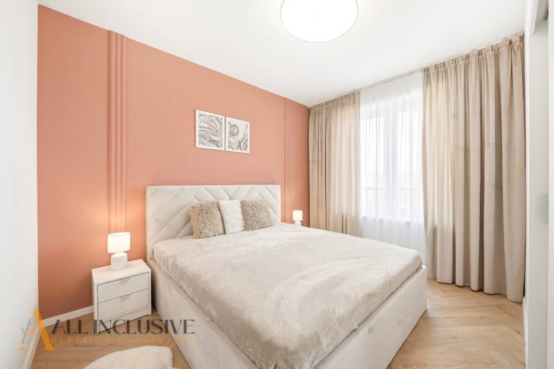 Hálószoba narancssárga fallal és fa mintázatú padlóval egy 4 szobás lakásban.