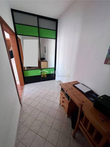 Szoros tér tárolószekrénnyel és faasztallal egy egyszobás lakásban.