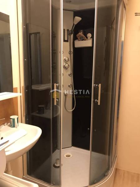 Fürdőszoba zuhanyzóval és mosdóval egy kétszobás lakásban.